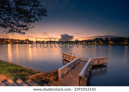 Sunset view on Xuan Huong lake, far away is Da Lat City with development buildings, transportation, market. Tourist city with center square of Da Lat city. Travel and landscape concept