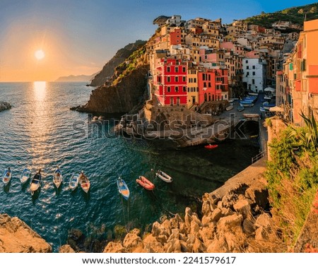 Sunset view onto the Mediterranean Sea with traditional boats and colorful houses in old town of Riomaggiore in Cinque Terre, Italy