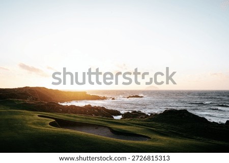 Sunset view over the Ailsa Course at Turnberry Golf Resort in Scotland, with the rugged coastline, rolling green fairway and waves of the Atlantic Ocean.