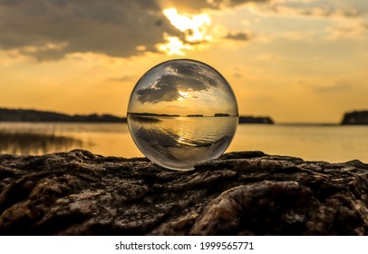 Sunset view over the lake through a glass ball. Transparent sphere on lake at sunset