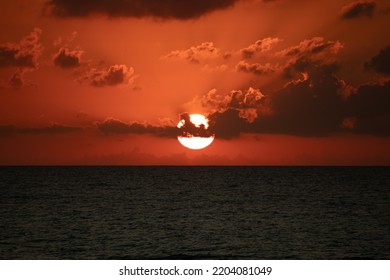 Sunset View, Sunset View Over The Sea. Orange Sky And Clouds, Twilight Colors. The Sun's Bright Round Disk Will Soon Disappear Behind Clouds. Summer Landscape Idea Concept. No People, Nobody.