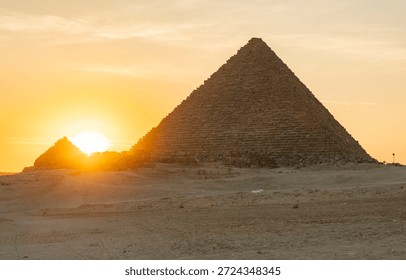 Sunset view of pyramid in desert with setting sun in background near Giza, Egypt