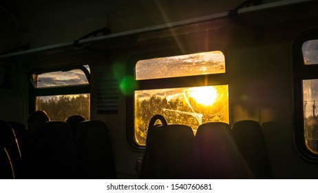Sunset view from a train window. Silhouetted passengers, golden light scenic landscape. 
