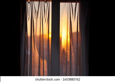 Sunset Warm Orange Light From The Sun Through The Tulle And Curtains On The Window. Low Key. Mood Toning.