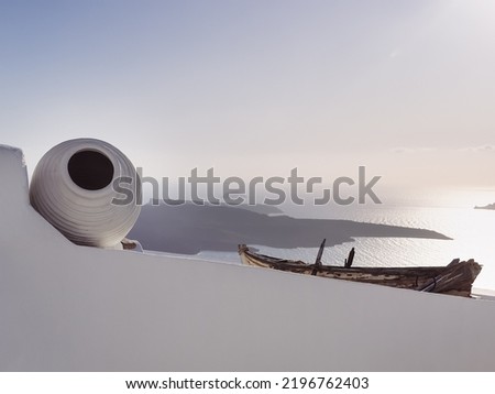 sunset from the white balcony on Santorini, the balcony is decorated with a white jug and an old boat, a beautiful seascape, copy space