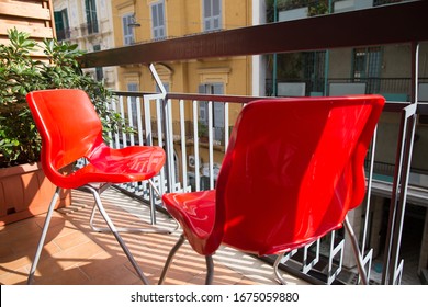 Sunshine Day Shot Of A Pair Of Two Modern Red Plastic Chairs Standing Outside On A Small Balcony Of An Apartment Building