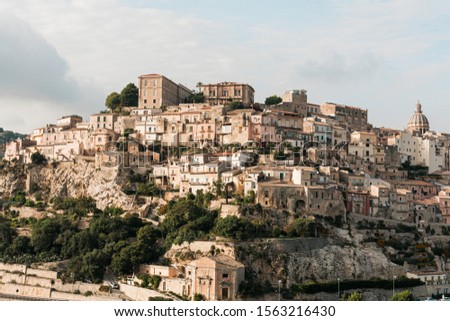 sunshine on trees near small houses in ragusa, italy 