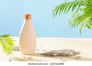 Suntan cream bottle on a beach with seashells and palm leaves. Sunscreen, sun protection lotion. Skin care and protection concept and travel. Golden tan. Copy space for text, mock up