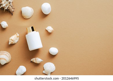 Suntan Cream Lotion Bottle And Seashells On Sandy Color Background. Flat Lay, Top View, Overhead.