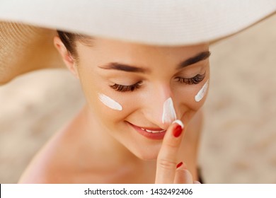 Suntan lotion woman applying sunscreen solar cream. Beautiful happy cute woman  applying suntan cream to her nose.