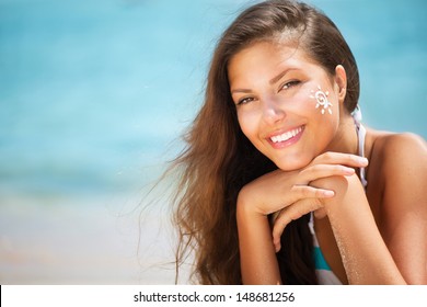 Suntan Lotion Woman Applying Sunscreen Solar Cream. Beautiful Happy Cute Girl Applying Sun Tan Cream On Her Face With Ocean In Background. Sun Tanning. Skin Protection