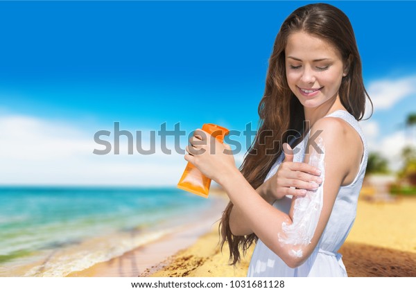 Suntan Lotion\
Woman Applying Sunscreen Solar Cream. Beautiful happy cute Girl\
applying Sun Tan Cream on her Face over ocean background. Sun\
Tanning. Skin care and Protection.\
Vacation