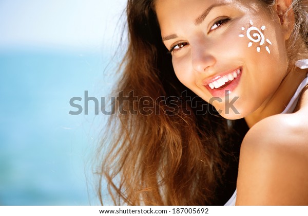 Suntan Lotion\
Woman Applying Sunscreen Solar Cream. Beautiful happy cute Girl\
applying Sun Tan Cream on her Face over ocean background. Sun\
Tanning. Skin care and Protection.\
Vacation