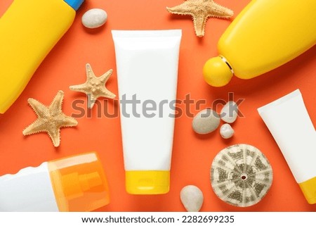 Suntan products and seashells on orange background, flat lay