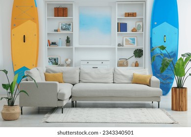 SUP boards, shelving unit with different decor elements and stylish sofa in room. Interior design - Shutterstock ID 2343340501