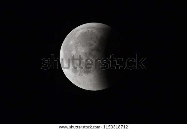 Super Bloody Moon, full eclipse last phase against\
black sky background, one third of the Moon surface covered by\
Earth\'s shadow