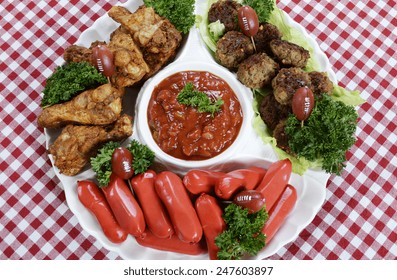 Super Bowl Sunday Football Party Celebration Food Platter With Chicken Buffalo Wings, Meat Balls, Hot Dogs And Salsa Dip On Red Check Table Cloth, Overhead.