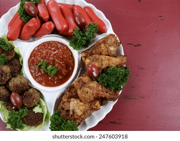 Super Bowl Sunday Football Party Celebration Food Platter With Chicken Buffalo Wings, Meat Balls, Hot Dogs And Salsa Dip On Red Wood Table, With Copy Space.