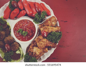 Super Bowl Sunday Football Party Celebration Food Platter With Chicken Buffalo Wings, Meat Balls, Hot Dogs And Salsa Dip On Red Wood Table, With Copy Space, With Applied Retro Style Filters.