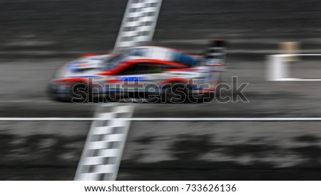 Super car race on the international race track crossing finish line with motion blur.