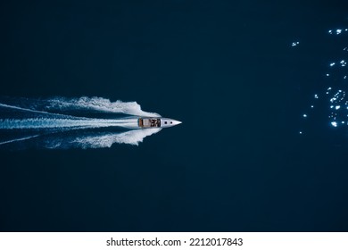 Super Fast Open Big Boat With People Moving Fast On Dark Blue Water Making A White Trail Behind The Boat.