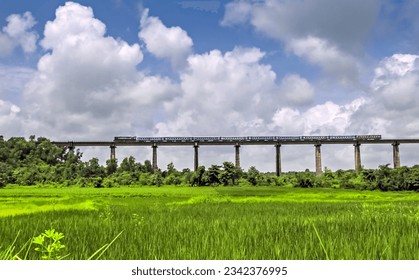 Super fast train crosses long viaduct at scenic location of green fields on Konkan Railway route. - Powered by Shutterstock