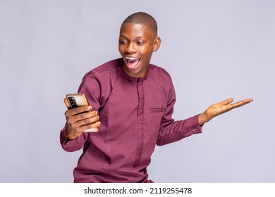 Super Happy African Guy In Authentic Costume Using Mobile Phone Celebrating Success Over White Background, Copy Space