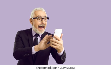 Super Happy Excited Bearded Senior Man In Suit And Glasses Has Got Unbelievable Incredible Sum Of Cashback And Is Looking At His Modern Mobile Phone With Open Mouth And Funny Surprised Face Expression