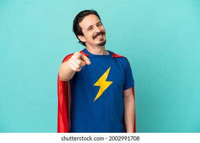 Super Hero caucasian man isolated on blue background pointing front with happy expression