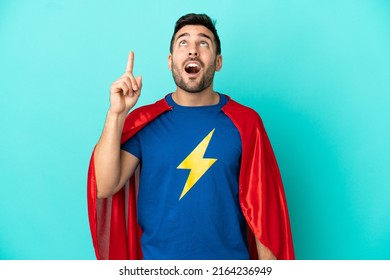 Super Hero Caucasian Man Isolated On Blue Background Pointing Up And Surprised