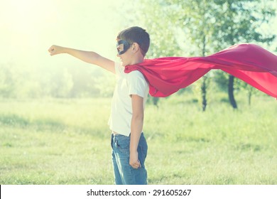 Super Hero Kid divirtiéndose al aire libre. Superhéroe pequeño boicot naturaleza fondo borroso verde