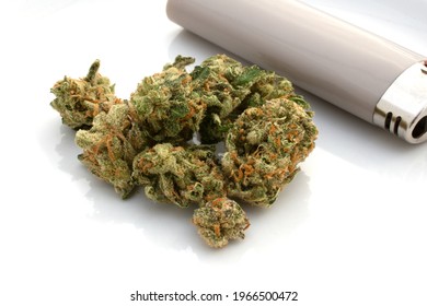 Super Lemon Haze Cannabis flower buds with a tan colored lighter on a white glossy surface. 
