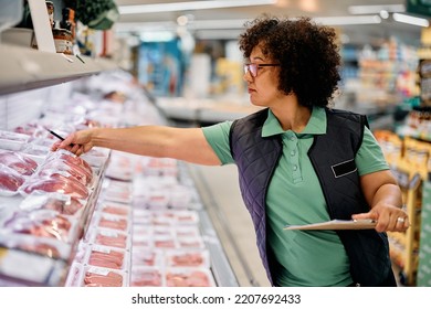 Super Market Manager Checking Frozen Products In Refrigerated Section. 