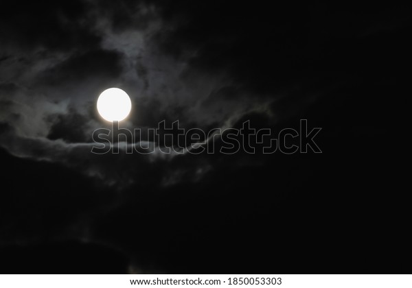 Super moon. An attractive photo of the night sky\
background with a cloudy and bright full moon. Night sky with a\
beautiful full moon.