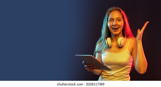 Super Offer. One Young Beautiful Girl Using Tablet Isolated On Dark Blue Studio Background. Concept Of Human Emotions, Facial Expression, Youth, Sales, Ad. Looks Shocked, Surprised. Flyer