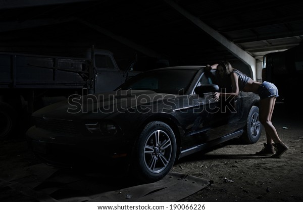 Super sexy chick with old muscle american black\
car in dusty garage