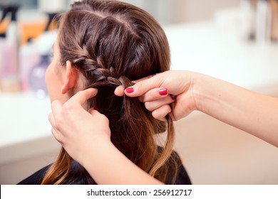 Super styling. Rear view closeup of a hairdresser braiding her clients hair in trendy weave plait while sitting in hairdressing salon
