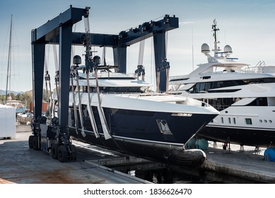 Super Yacht hauled out in shipyard, being lifted by industrial crane for refit or maintenance yard period  - Shutterstock ID 1836626470