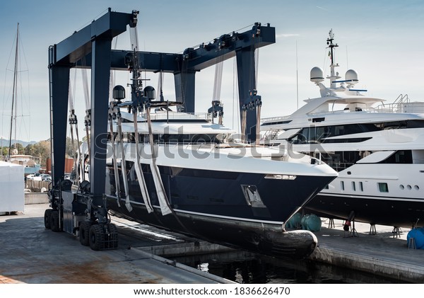 Super Yacht hauled out\
in shipyard, being lifted by industrial crane for refit or\
maintenance yard period 