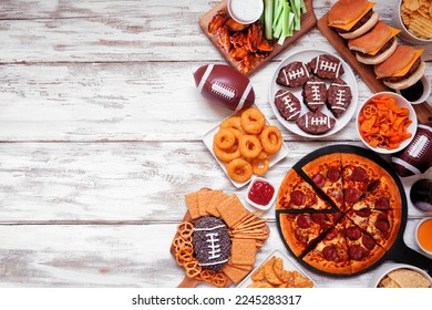 Superbowl or football theme food side border. Pizza, hamburgers, wings, snacks and sides. Overhead view on a white wood background.