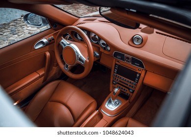 Supercar interior, view through the sunroof. Close-up view of expensive car interior with comfortable leather seats and dashboard 