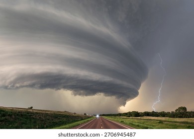 Supercell thunderstorm with dramatic storm clouds and lightning over a road in Nebraska.