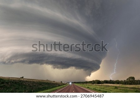 Supercell thunderstorm with dramatic storm clouds and lightning over a road in Nebraska.