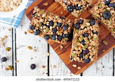 Superfood Breakfast Bars With Oats And Blueberries On Wood Board, Overhead Scene On Rustic Background