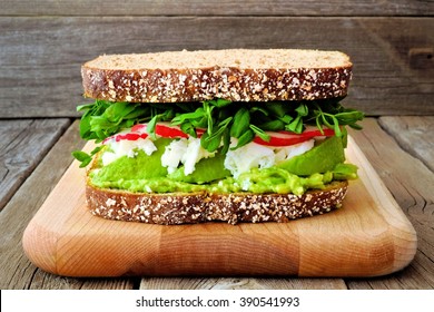 Superfood Sandwich With Avocado, Egg Whites, Radish And Pea Shoots On Whole Grain Bread Against A Rustic Wood Background