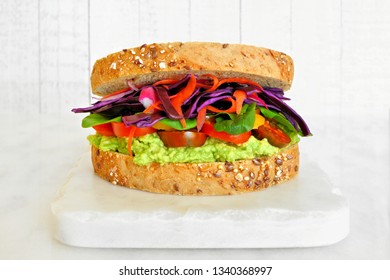 Superfood Sandwich With Avocado, Tomatoes, And Vegetables On Whole Grain Bread. Side View On A Marble Serving Board Against A Bright Background.