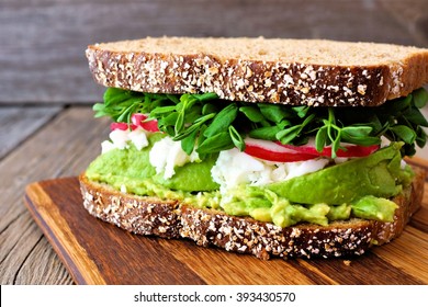 Superfood Sandwich With Whole Grain Bread, Avocado, Egg Whites, Radishes And Pea Shoots On Wood Board