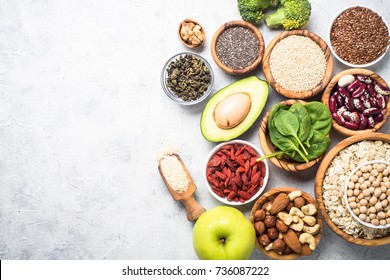 Superfoods on a gray background with copy space. Nuts, beans, greens and seeds. Healthy vegan food.