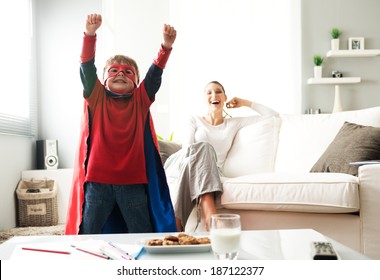 Superhero boy having an healthy snack with cookies and milk with his mother on background. - Powered by Shutterstock