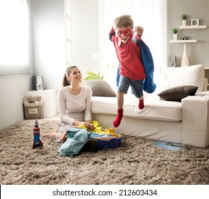 Superhero boy and his mother doing laundry together in the living room. - Powered by Shutterstock